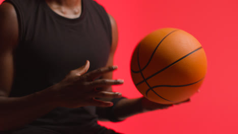 Nahaufnahme-Eines-Männlichen-Basketballspielers,-Der-Den-Ball-Vor-Rotem-Hintergrund-Von-Hand-Zu-Hand-Wirft-1
